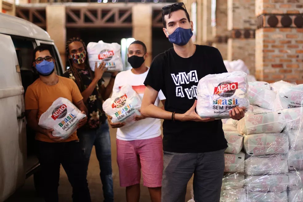 Pessoas segurando cestas de alimentos com a logo Ação Cidadania